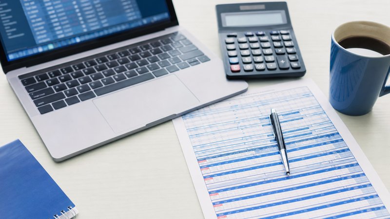 A calculator, a laptop and a printed odds sheet with a pen on a tidy analysis desk